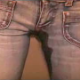An attractive German girl pees in her tight jeans and speaks to the camera.
